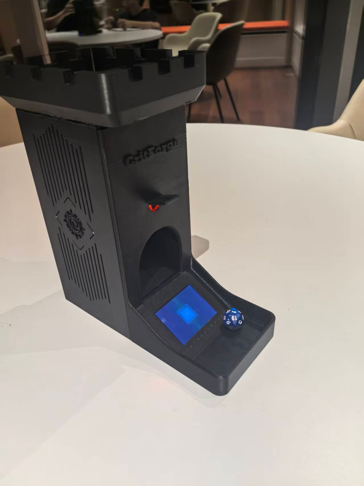 Smart dice tower prototype with blue screen and d20 die